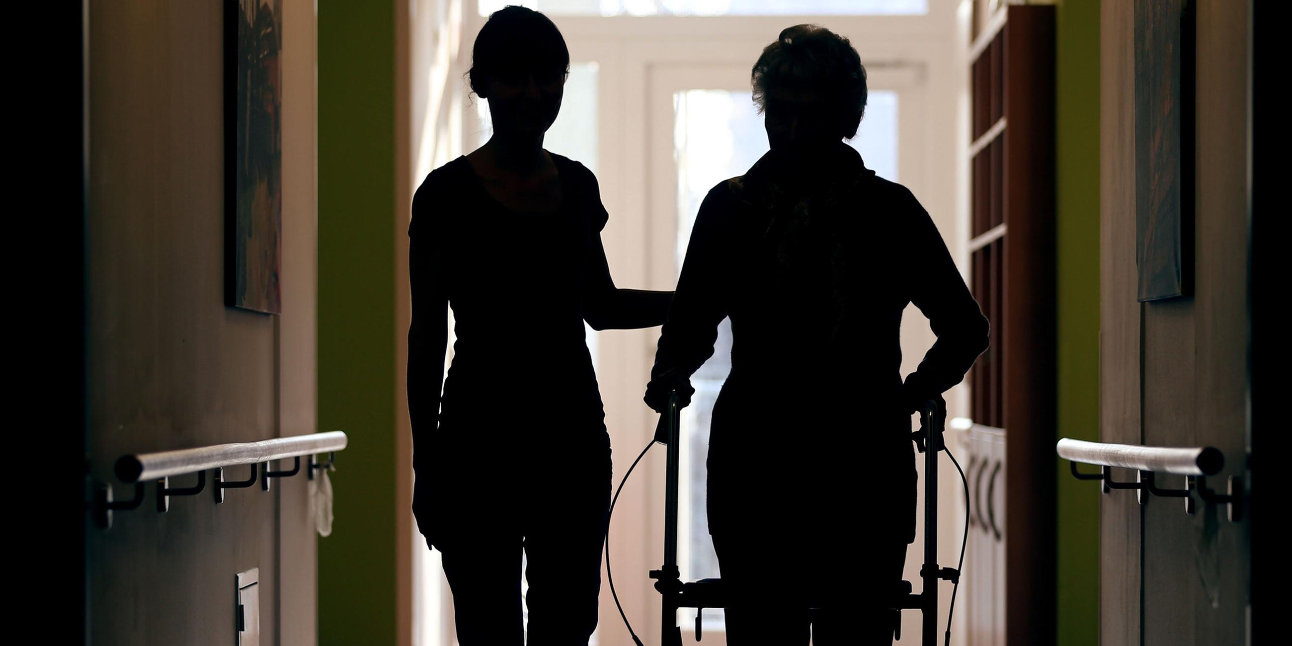 Une Pflegekraft accompagne une résidente d'un Altenheim sur le couloir