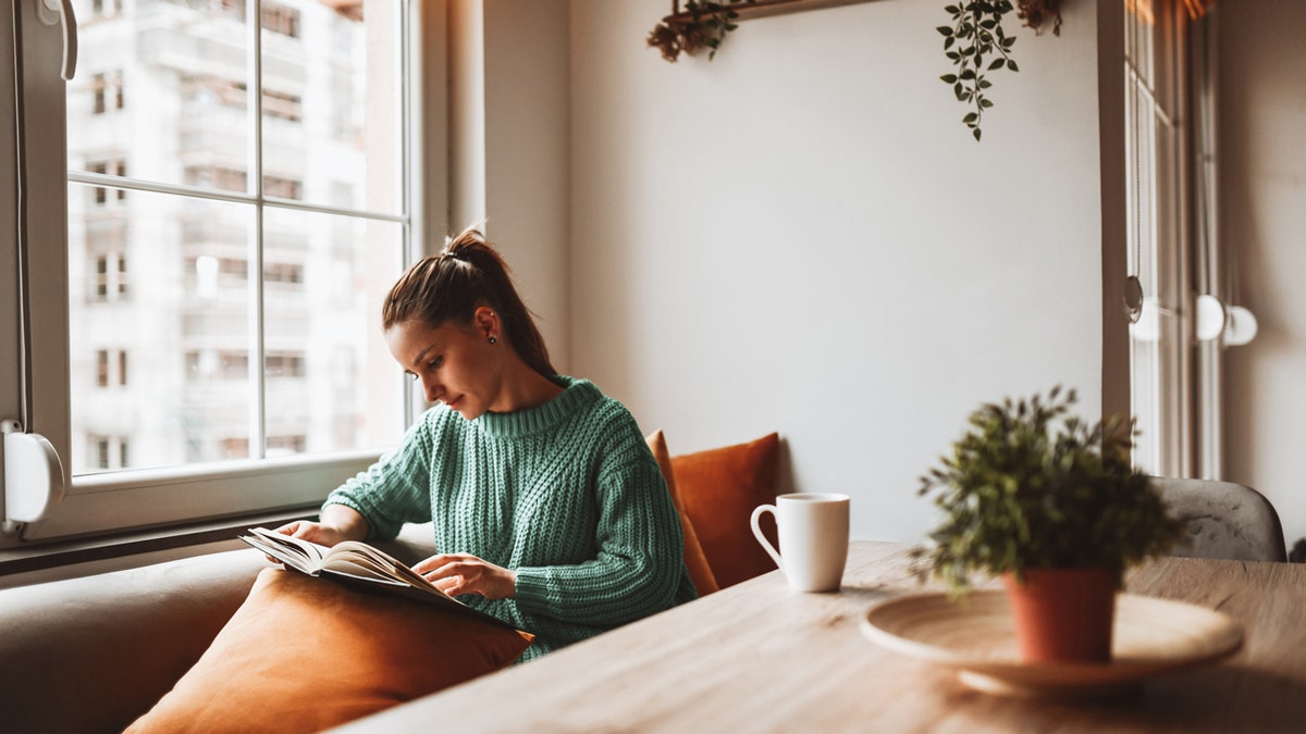 Femme lisant un livre chez elle