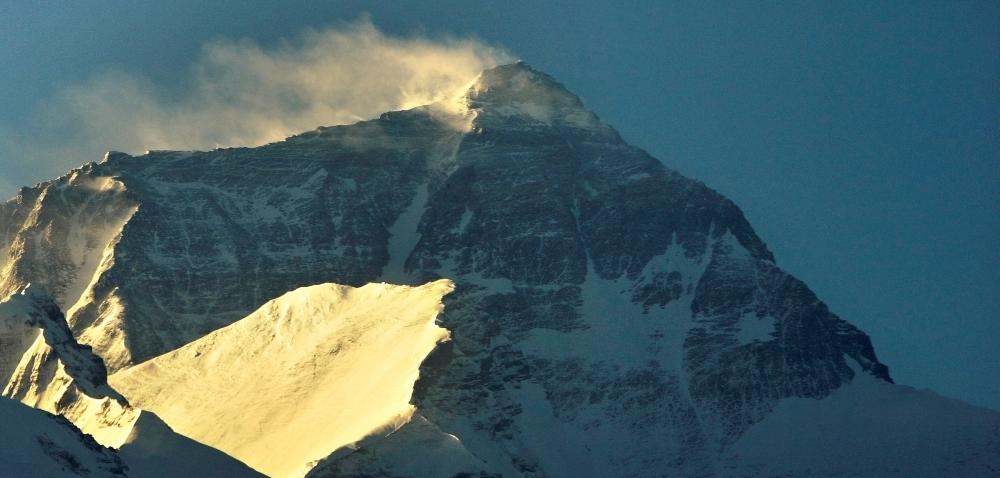 Le vent souffle la neige du sommet du plus haut sommet du monde au lever du soleil