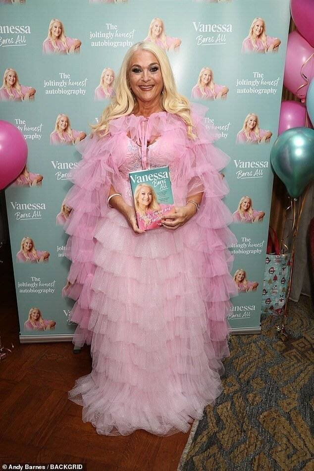 Vanessa Feltz dans une robe rose pastel accompagnée d'une cape rose.