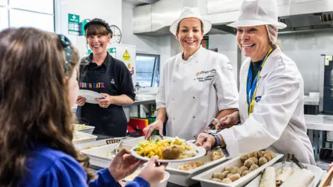 Une jeune écolière reçoit une assiette de nourriture