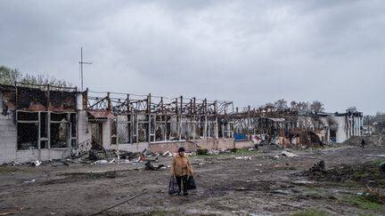 Une femme marche dans les ruines de Trostianets, dans la région de Soumy en Ukraine, le 19 avril 2022. (VIRGINIE NGUYEN HOANG / HANS LUCAS / AFP)