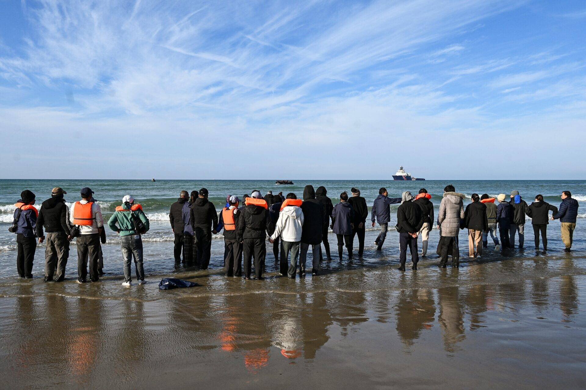 Des migrants attendent pour monter à bord d'un bateau de passeurs sur la plage d'Audresselles, dans le nord de la France, le 25 octobre 2024.