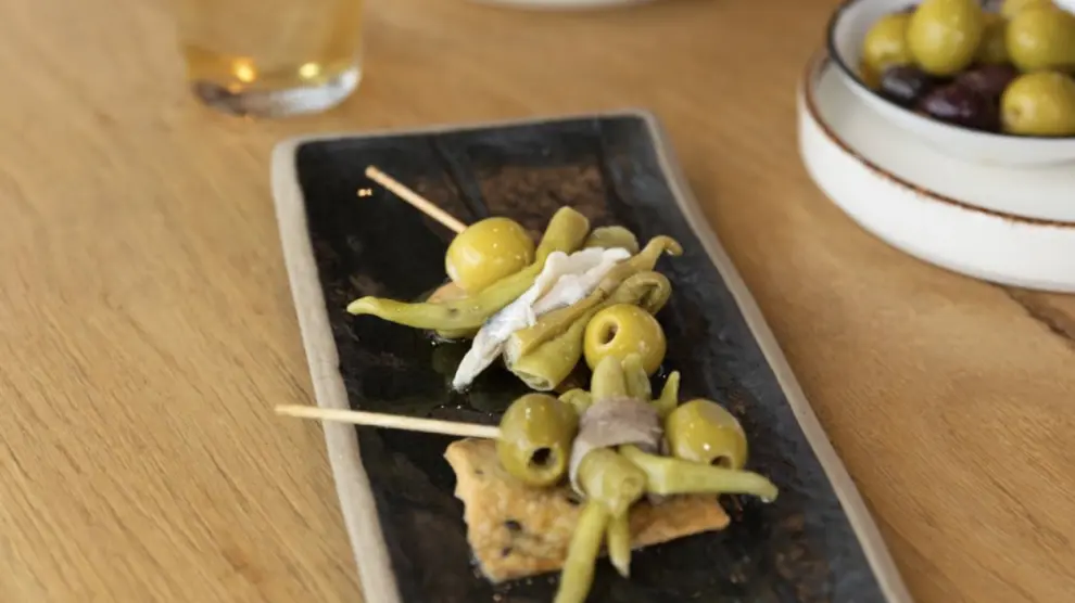 Plato de Gildas accompagné d'autres olives sur une table en bois