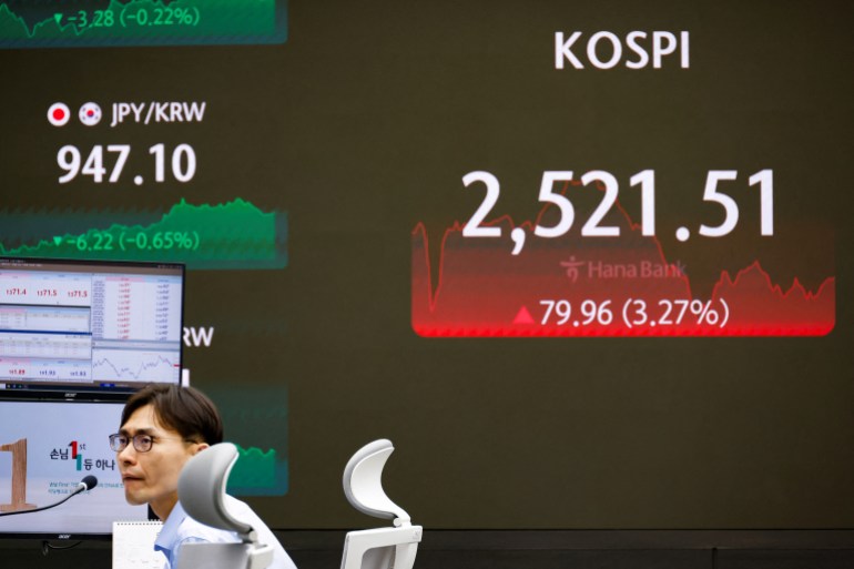 Un vendeur de devises travaille devant un tableau électronique affichant l'indice KOSPI en Corée du Sud.