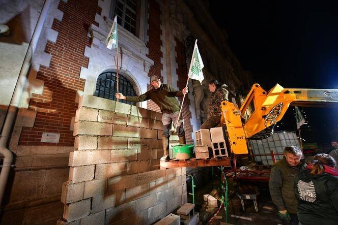 Des agriculteurs de la FNSEA construisent un mur de briques devant le bureau du député PS François Hollande à Tulle, le 6 décembre 2024.
