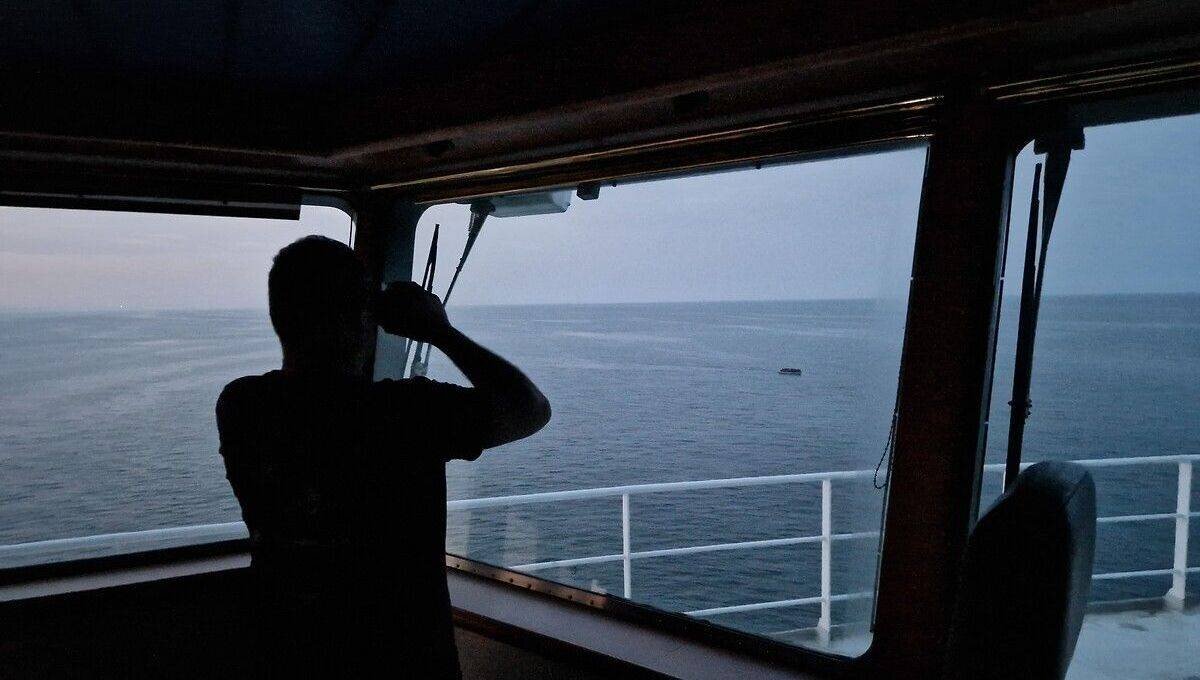 Le commandant de l'Abeille Normandie observe une embarcation de migrants avec ses jumelles