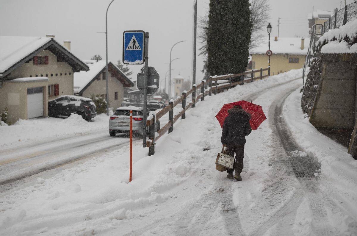 Une femme marche sur une rue enneigée à Ollon, Crans-Montana, le 23 décembre 2024.