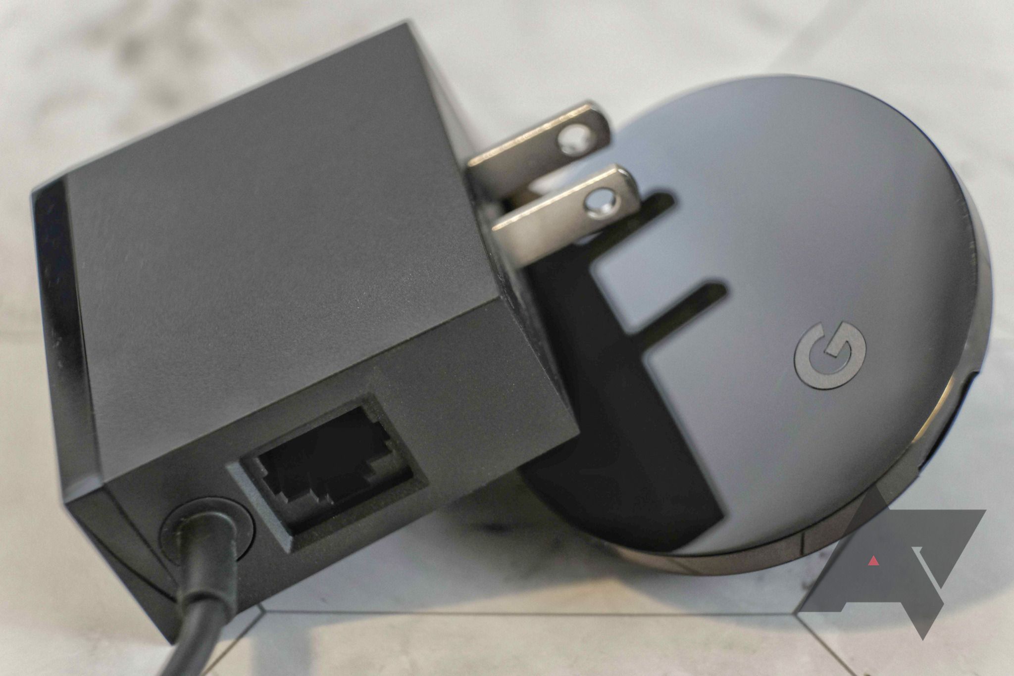 A Google Chromecast Ultra with its extra Ethernet adapter laying next to it.