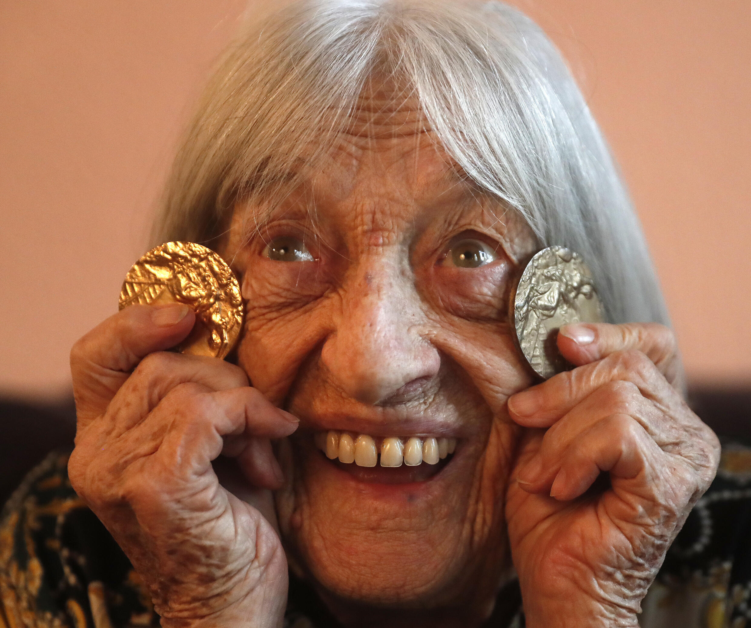 Agnes Keleti pose avec deux de ses médailles olympiques dans son appartement de Budapest, en Hongrie, le mercredi 8 janvier 2020.
