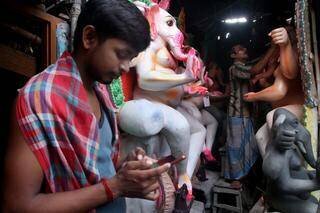 Un jeune Indien consulte son téléphone portable devant une statue du dieu hindou Ganesh, le 30 août 2019, à Calcutta.