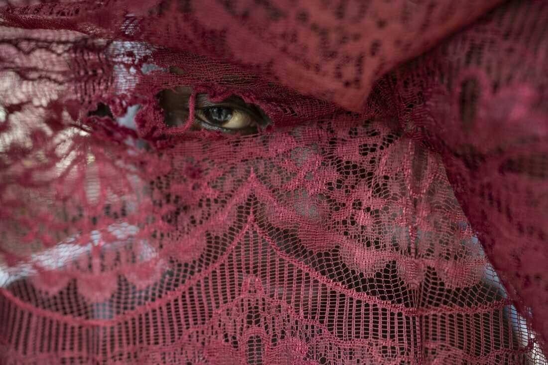 Camilo Garcia peeks through a curtain of his house on the morning of March 29, 2024, in the town of Juntas, Buenaventura, Colombia.