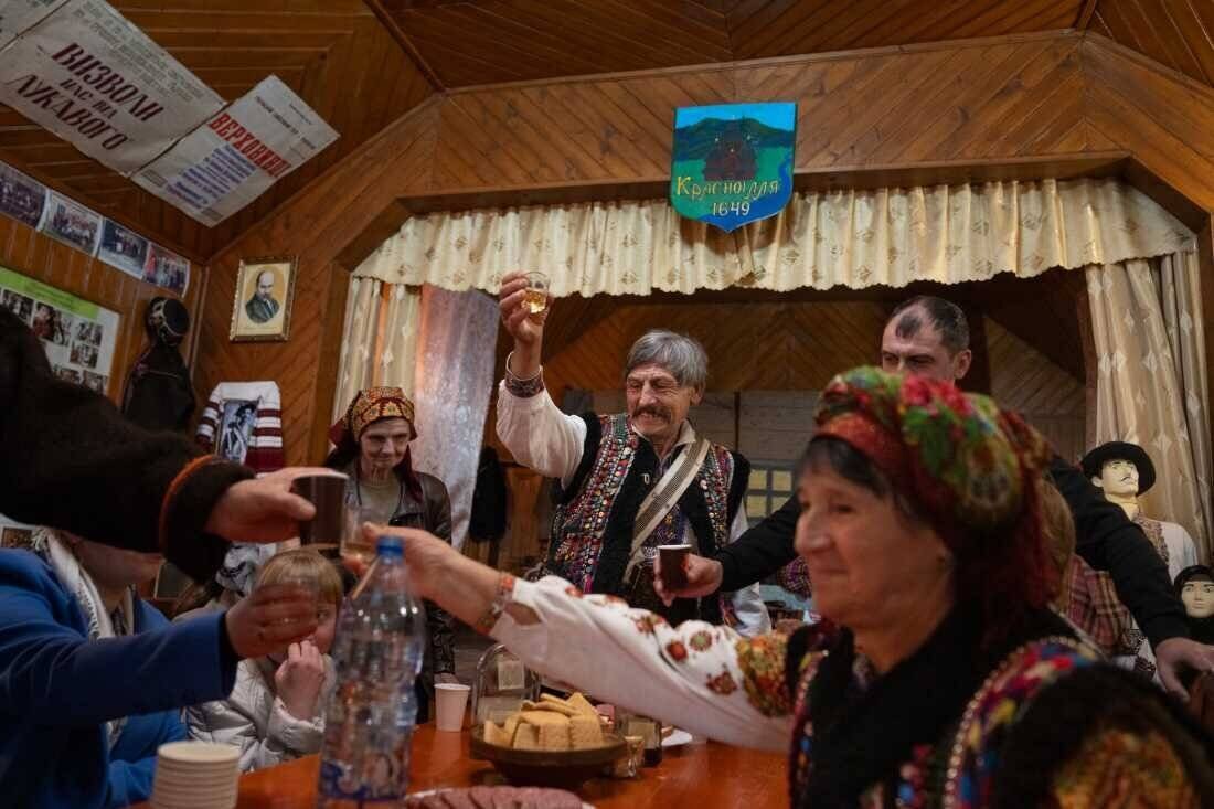 After a rehearsal, members of the Hutsul Theater troupe have drinks and share some meats and cheeses together on Nov. 3 in Krasnoillya, Ukraine.