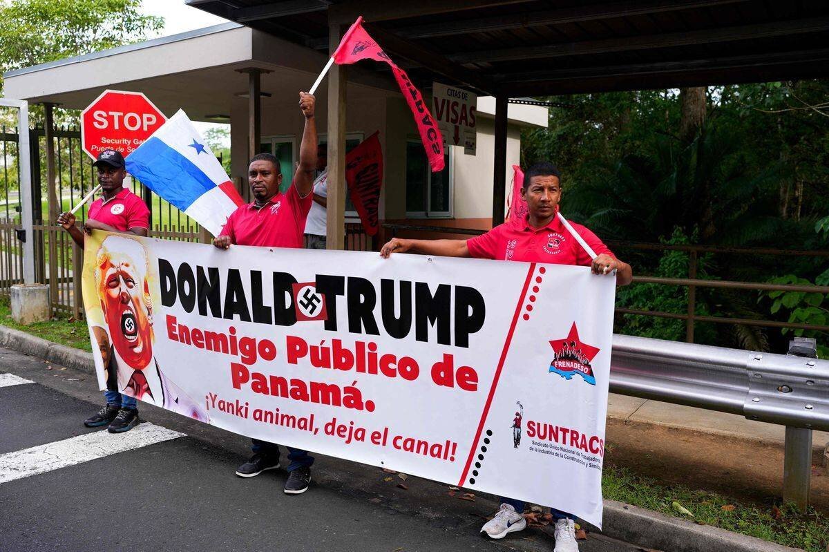 Demonstrants protestent devant l'ambassade des États-Unis à Panama le 24 décembre 2024, avec une banderole indiquant 'Donald Trump Enemigo Público de Panamá. Yankee Animal, deja el canal!'.