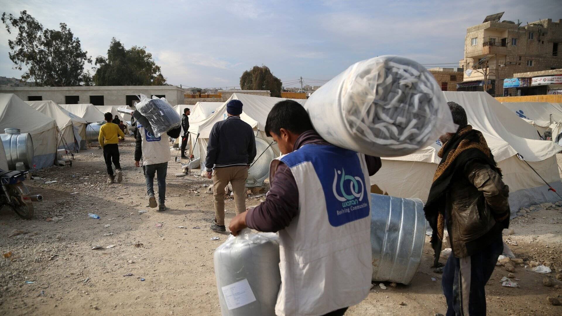 Des personnes déplacées en Syrie transportent des aides humanitaires vers un camp de réfugiés.