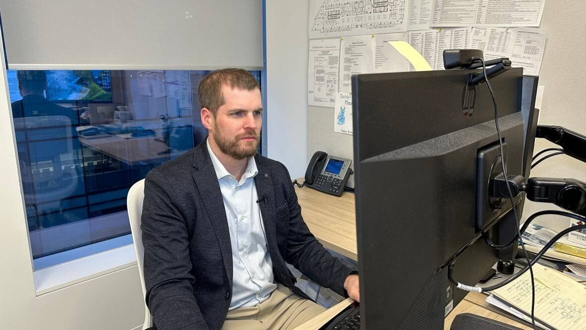 John Boyle à un ordinateur avec un costume et une chemise.