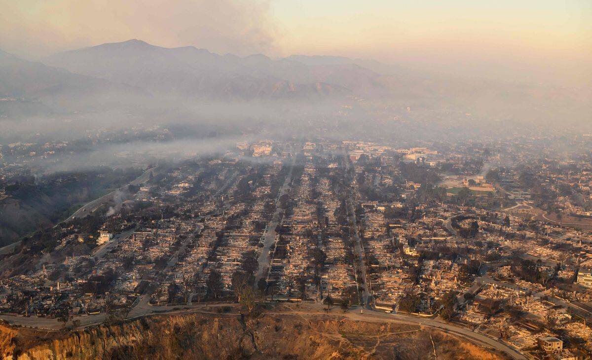 Aerial view of houses destroyed by the Palisades fire in Los Angeles on January 9, 2025, with smoke in the sky.