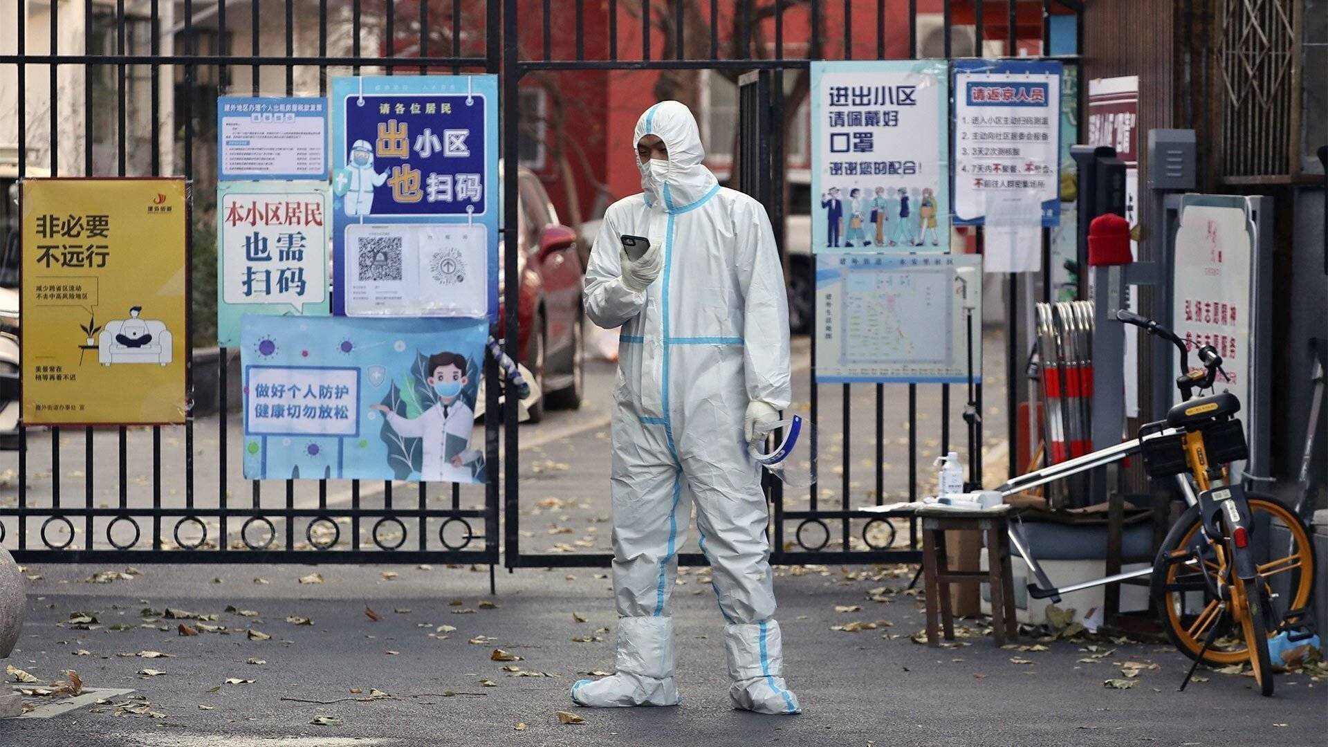 Arbeiter im Schutzanzug vor dem Tor eines abgesperrten Viertels.