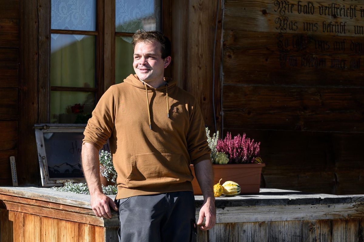 Benjamin Ramseier se tient devant un bâtiment en bois sur sa ferme à Röthenbach dans l'Emmental.