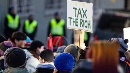 Une pancarte appelle à 'taxer les riches' dans une manifestation contre le Forum économique mondial, à Davos (Suisse), le 14 janvier 2024.