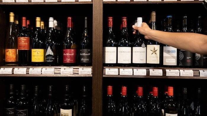 Une personne attrape une bouteille de vin.