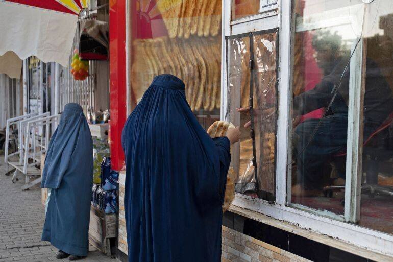 Une femme afghane achète du pain traditionnel dans une boulangerie.