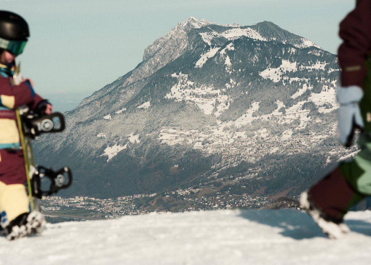 Deux petits enfants en équipement de snowboard marchent sur une surface enneigée.