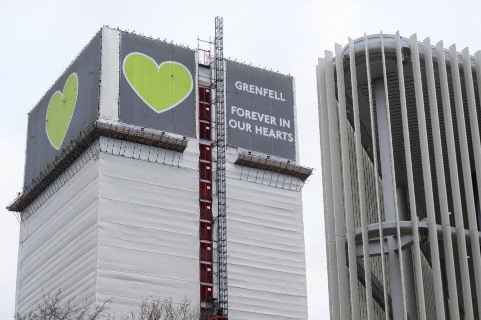 Grenfell Tower enveloppée dans des protections, avec une bannière 'Grenfell Forever in Our Hearts.'