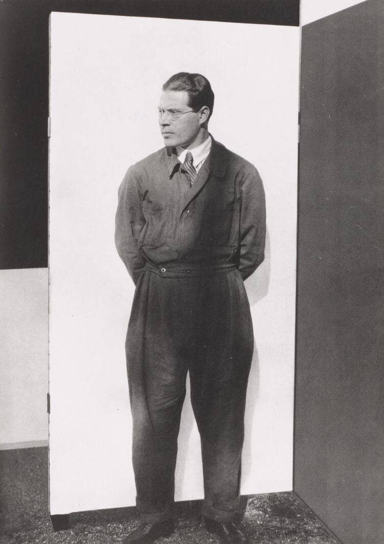 Un homme en costume devant un mur bicolore.