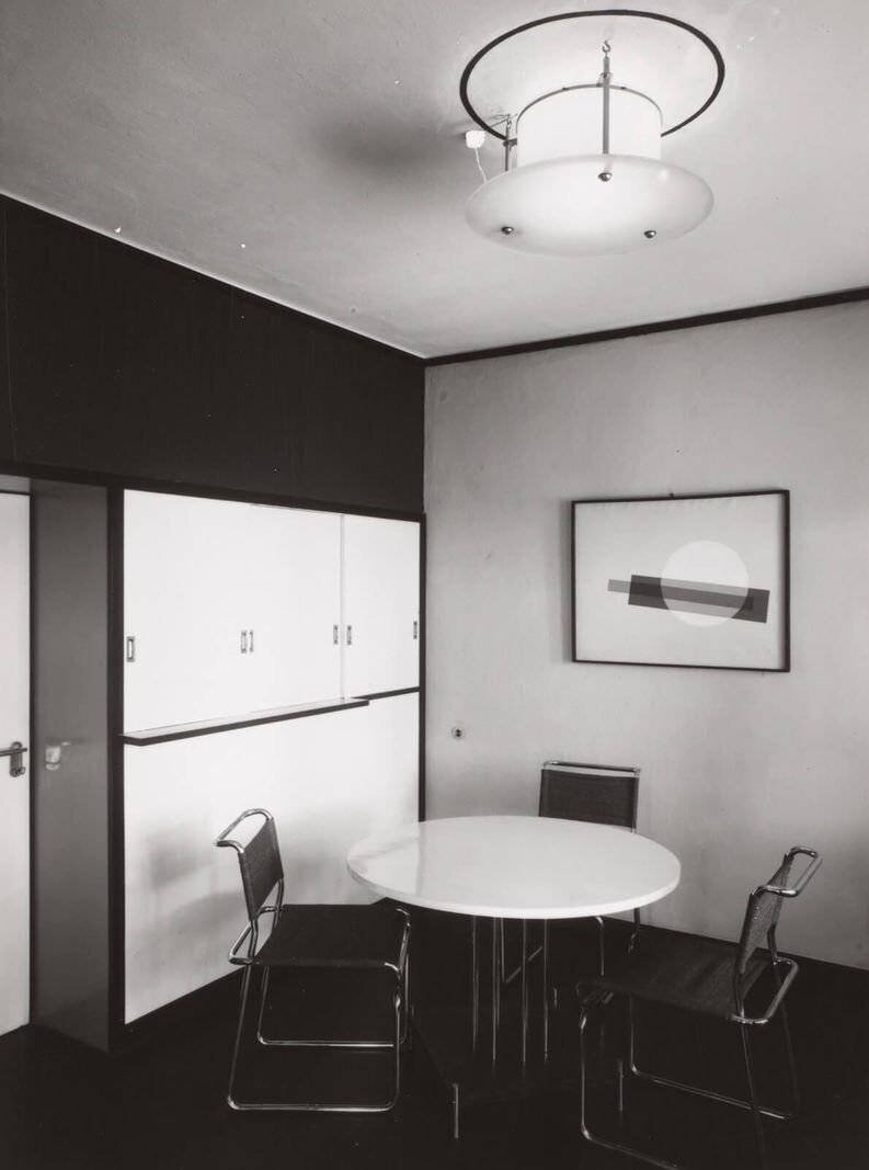 Un intérieur en noir et blanc avec une table ronde et trois chaises.