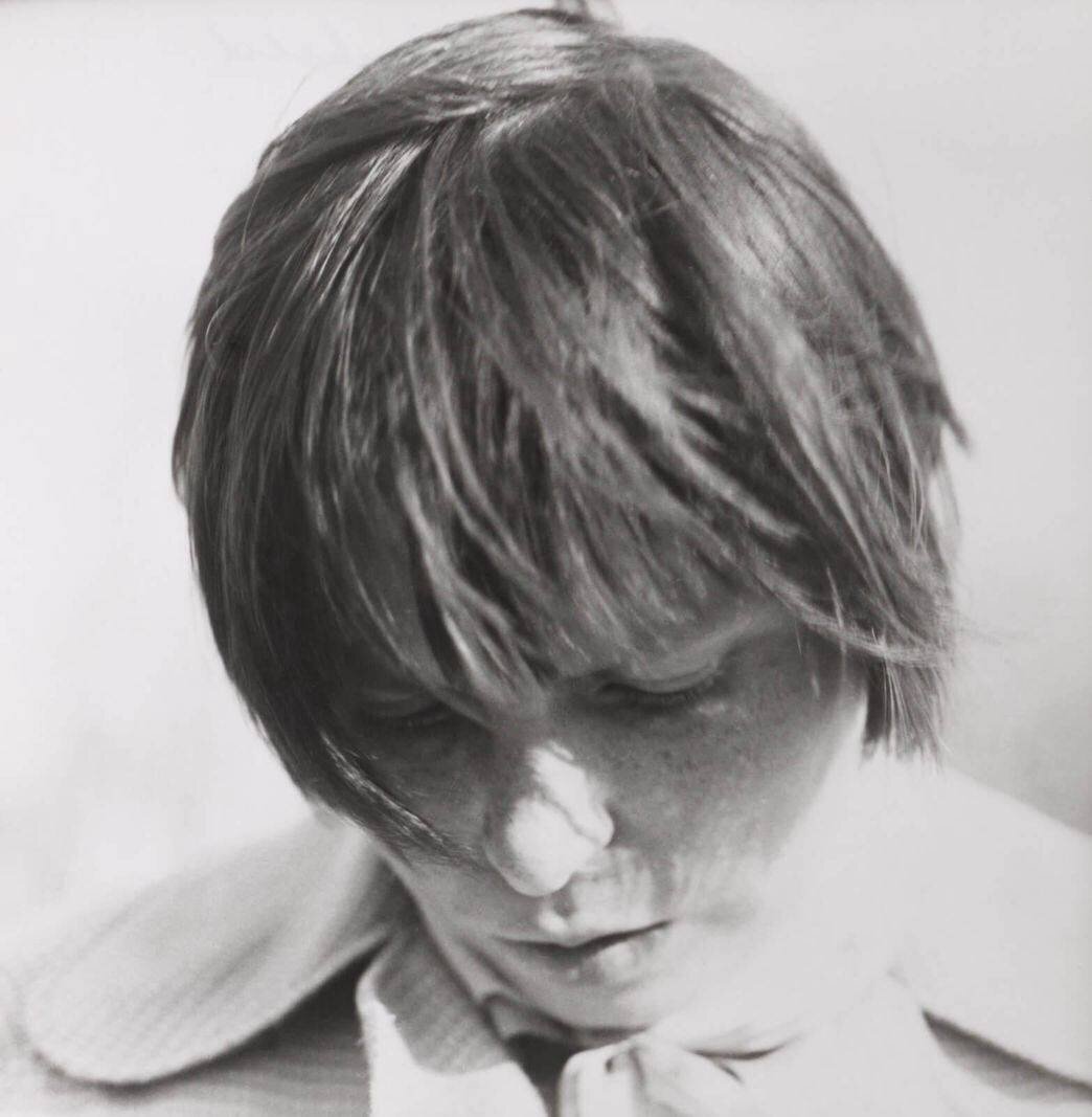 Photographie en noir et blanc d'une personne avec un regard pensif.