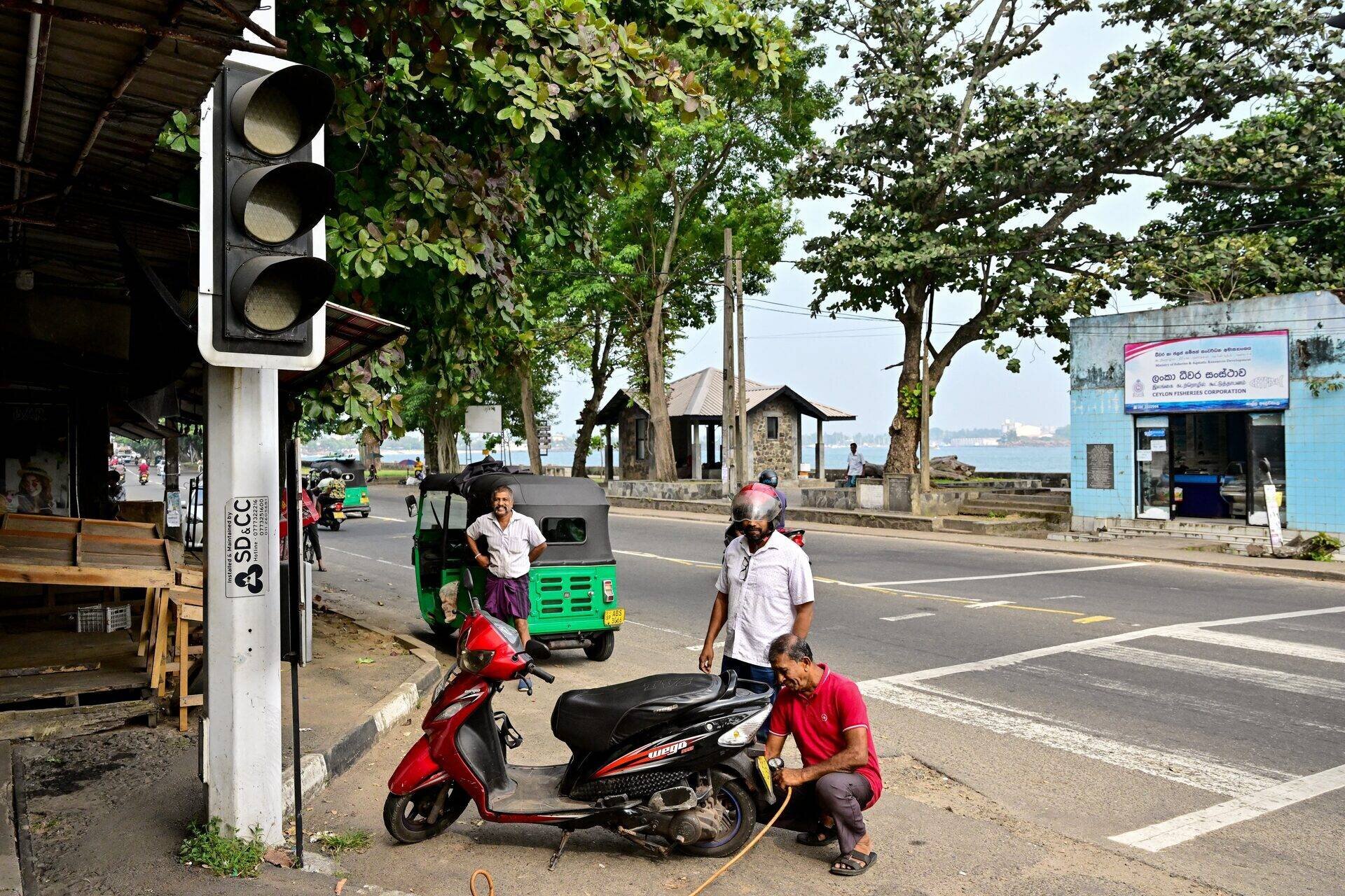 Sri Lankans stand beside an inoperative traffic light following a nationwide power outage in Galle