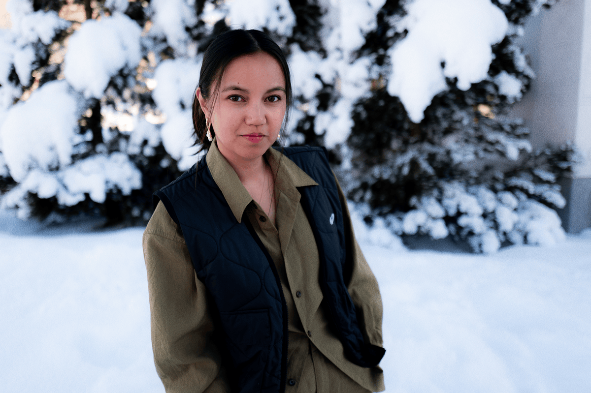 Jessica Rees, une femme posant devant des arbres enneigés, portant une chemise kaki et une veste noire sans manches.