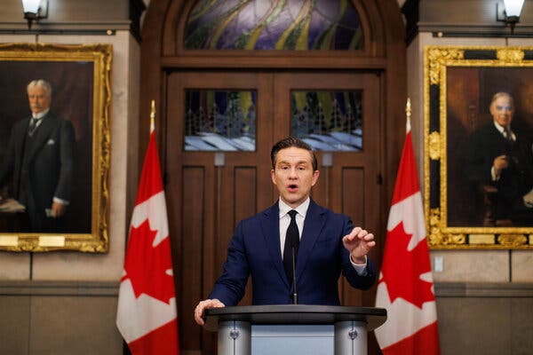 Pierre Poilievre s'exprimant lors d'une conférence de presse, flanqué de deux drapeaux canadiens.