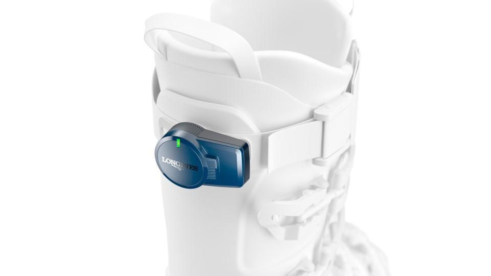 Chaussure de ski blanche avec un dispositif électronique bleu sur le côté.