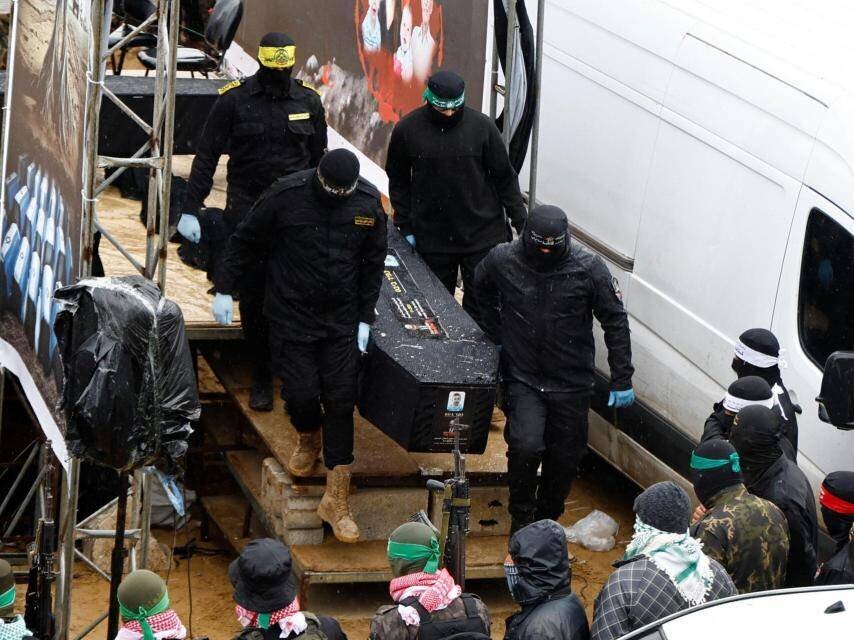 Miliciens de Hamás avec l'un des cadavres livrés à Israël.