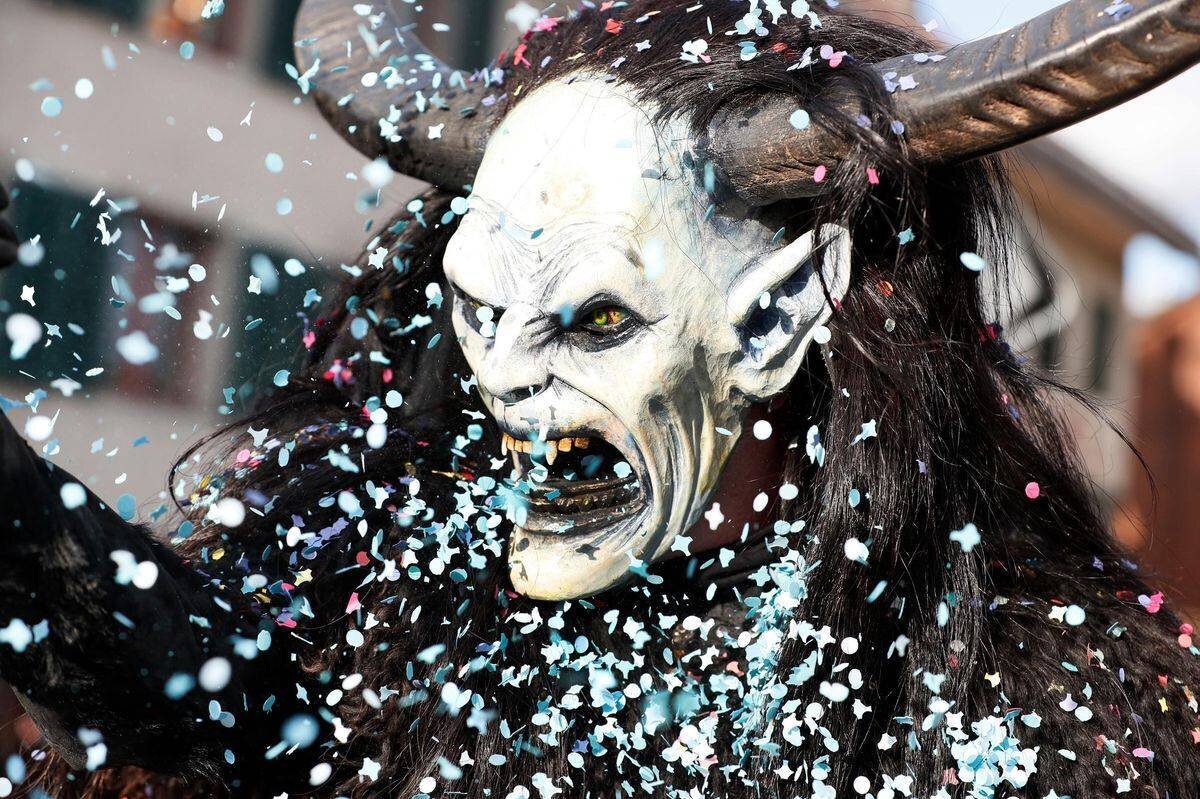 Fasnachtsmaske beim Umzug in Bassersdorf, mit Konfetti und erschreckendem Gesichtsausdruck.