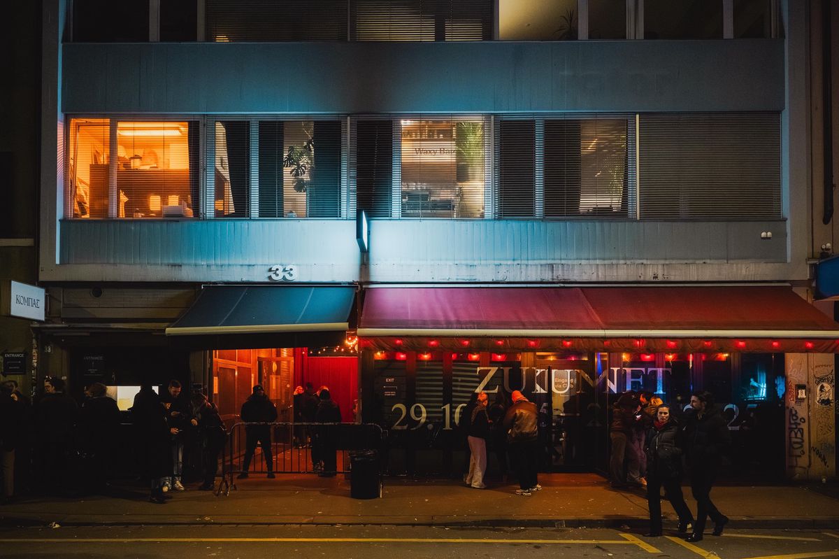 Vue nocturne du bâtiment du club 'Das Ende der Zukunft' avec des fenêtres illuminées.