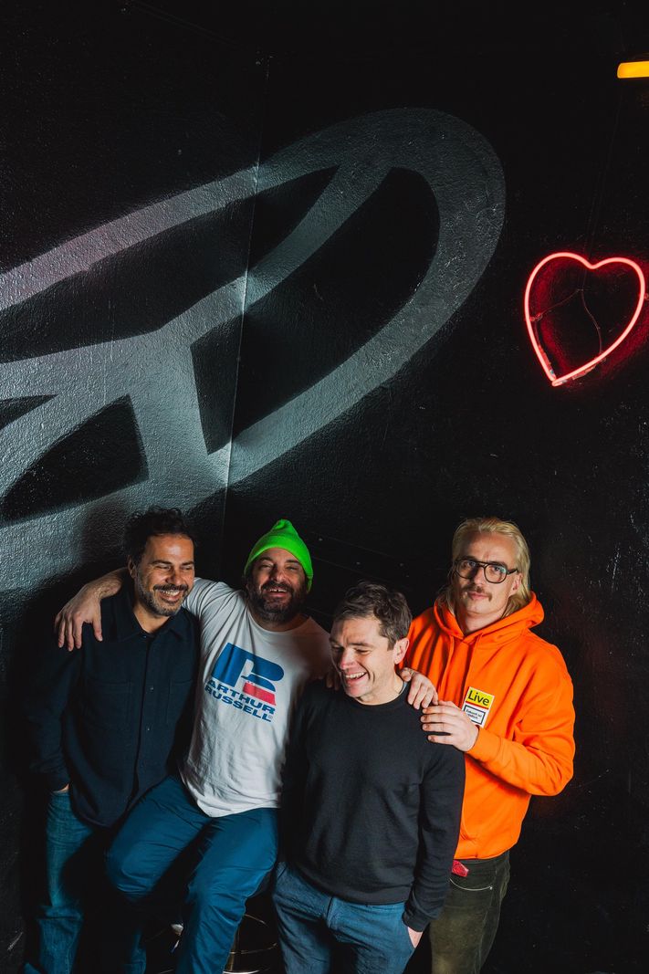 L'équipe du Club Zukunft pose devant un mur noir avec une œuvre d'art néon.
