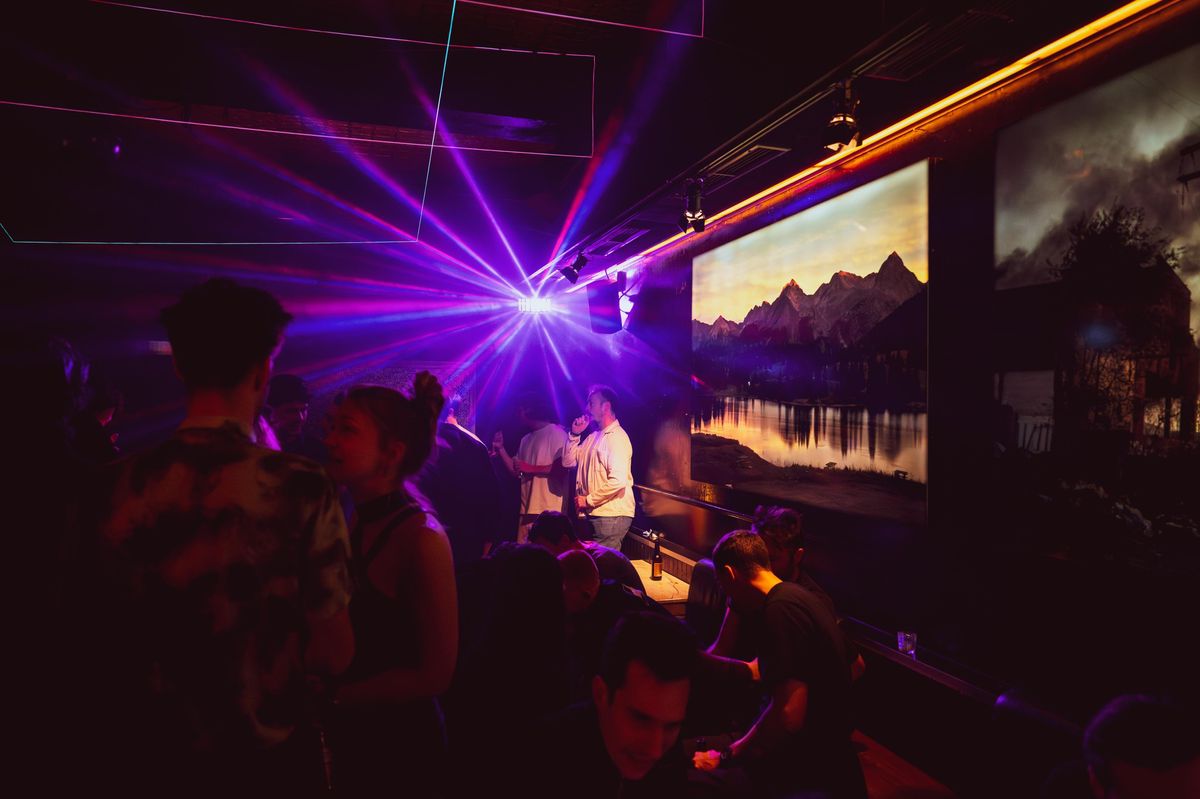 Intérieur d'un club avec des lumières colorées et une ambiance festive.