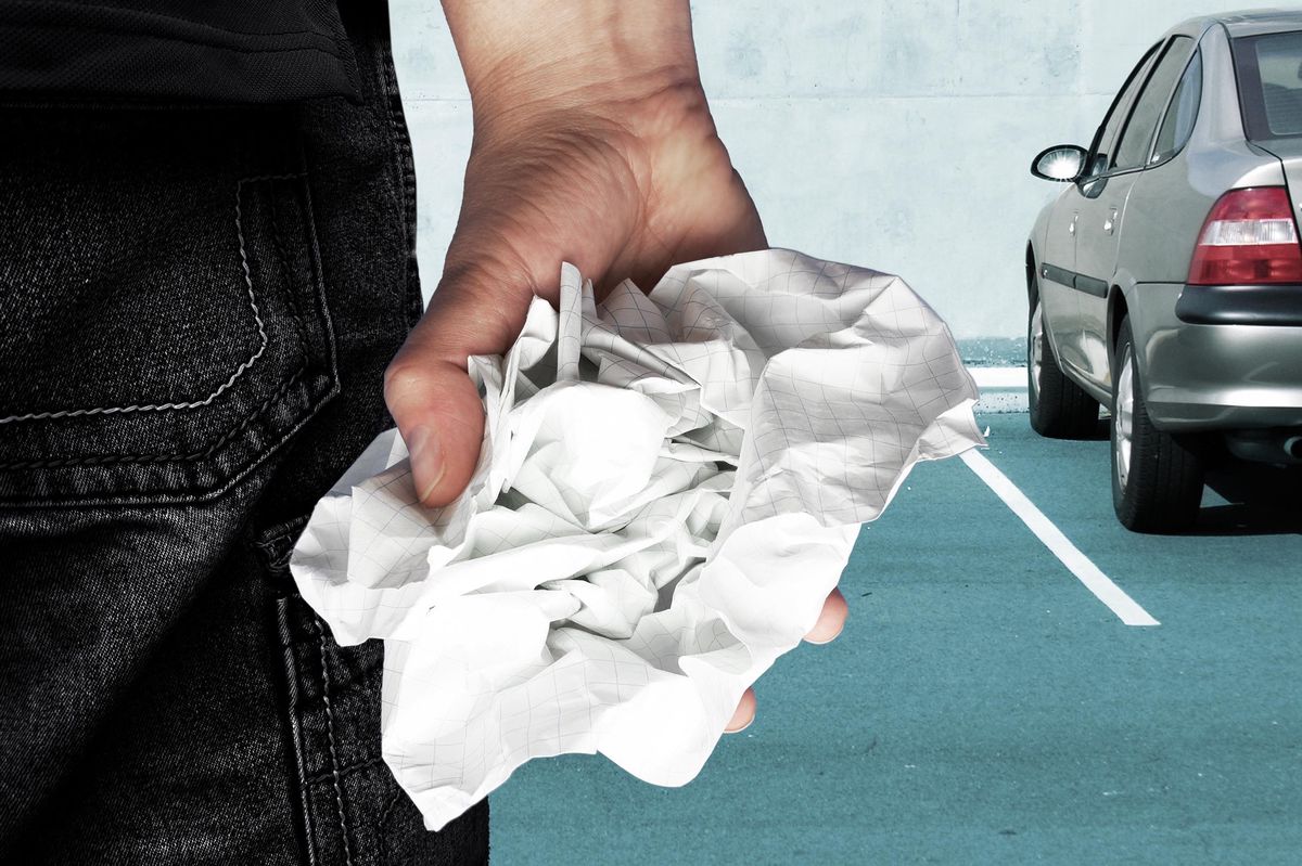 Une personne tenant un papier froissé sur un parking.