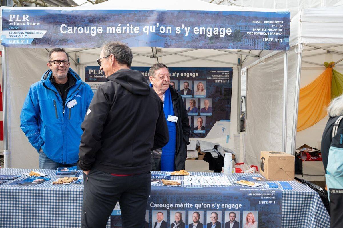 Stands de campagne pour les élections municipales 2025 à Carouge, place du Marché, avec affiches et brochures.