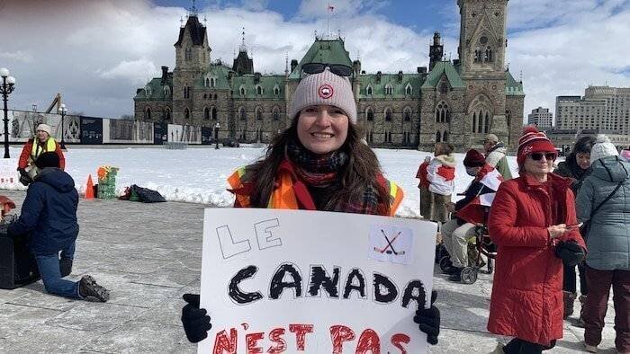 Portrait de Samantha McBeth qui tient une pancarte sur laquelle il est écrit «Le Canada n'est pas à vendre», sur la colline du Parlement.