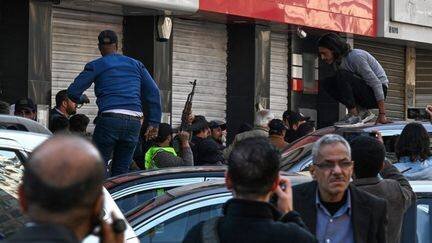 Des hommes armés à Damas lors de manifestations en lien avec les violences entre la communauté alaouite et les forces de sécurité.