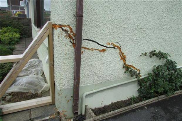 Fissures importantes sur le mur extérieur d'une maison.
