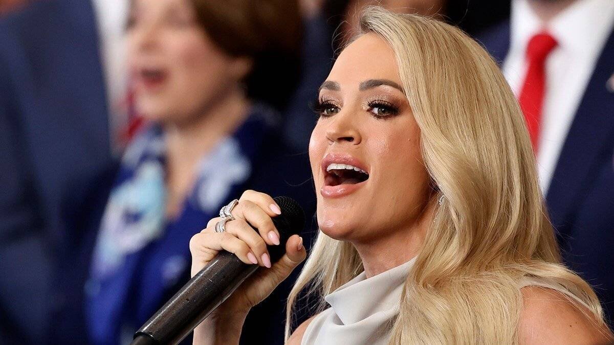 Carrie Underwood sings into the phone while looking out into the audience