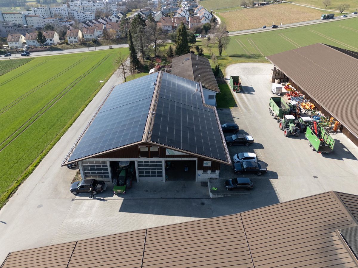 Mattenhof à Regensdorf avec la nouvelle installation solaire sur le toit, entouré de bâtiments agricoles, Photographe : André Springer.