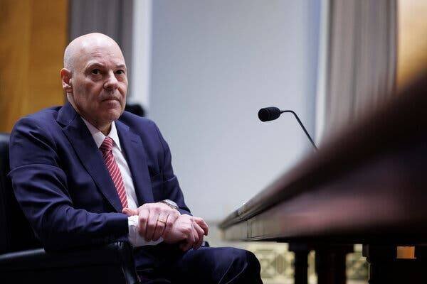 Louis DeJoy, directeur général du service postal américain, en bleu avec une cravate rayée rouge.