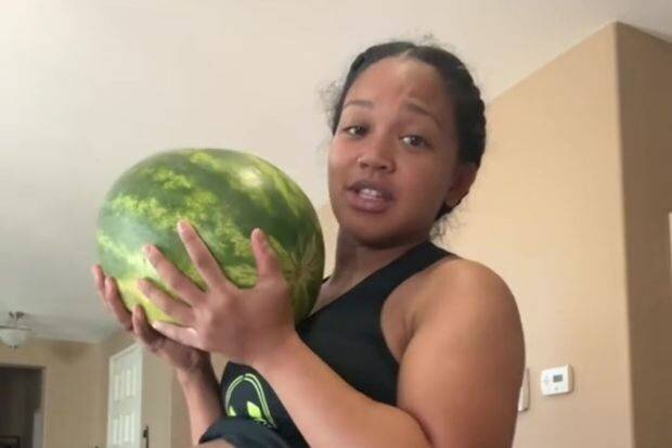Une femme enceinte tenant une pastèque, comparant sa taille à son ventre de grossesse