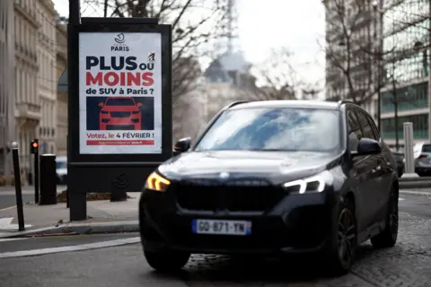 Un SUV passe devant une affiche à Paris pour un vote sur l'augmentation des frais de stationnement